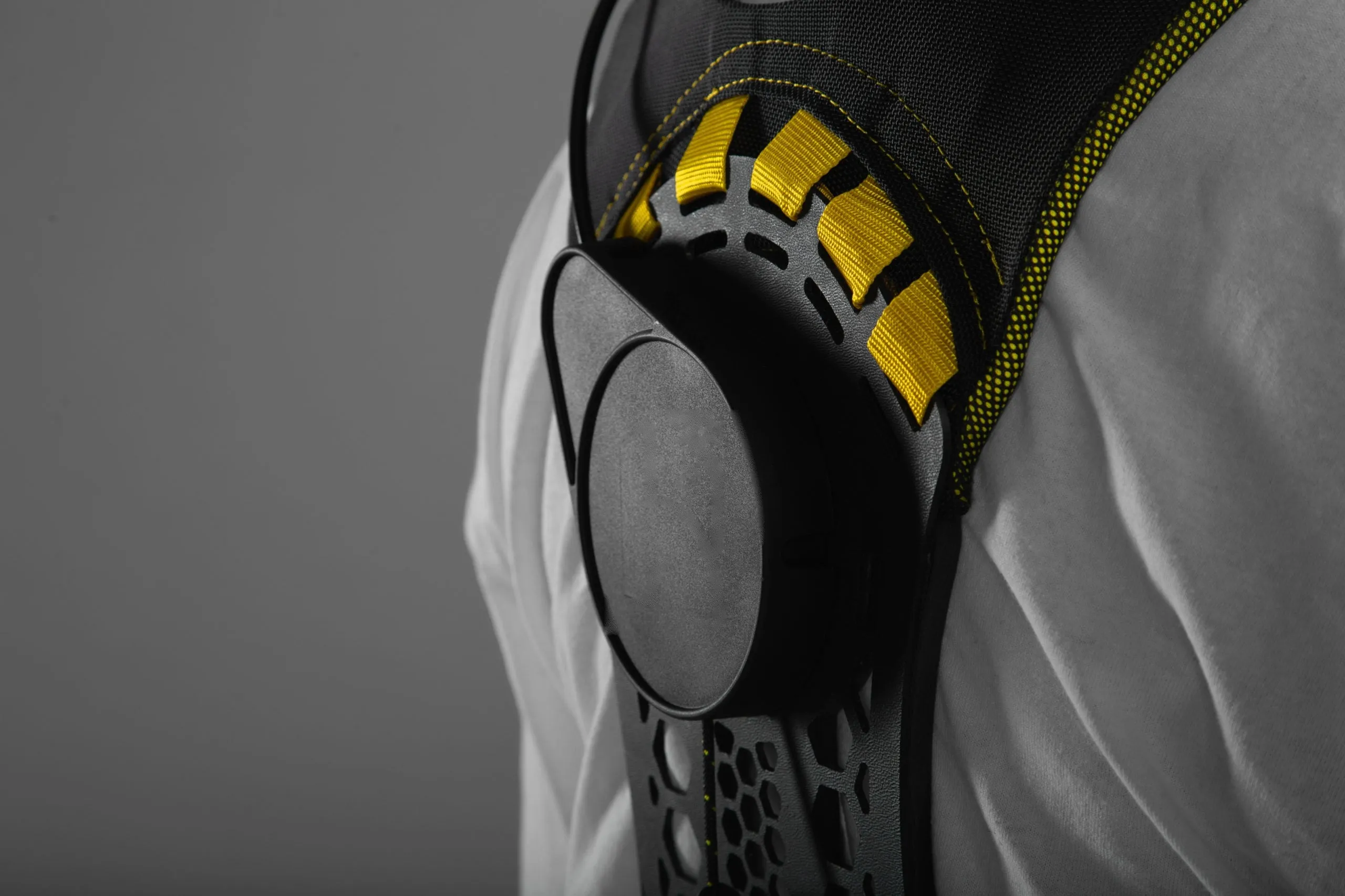 Close detail of the Apex 2 back unit over a worker’s shoulder, the yellow elastic bands running through the black molded shell