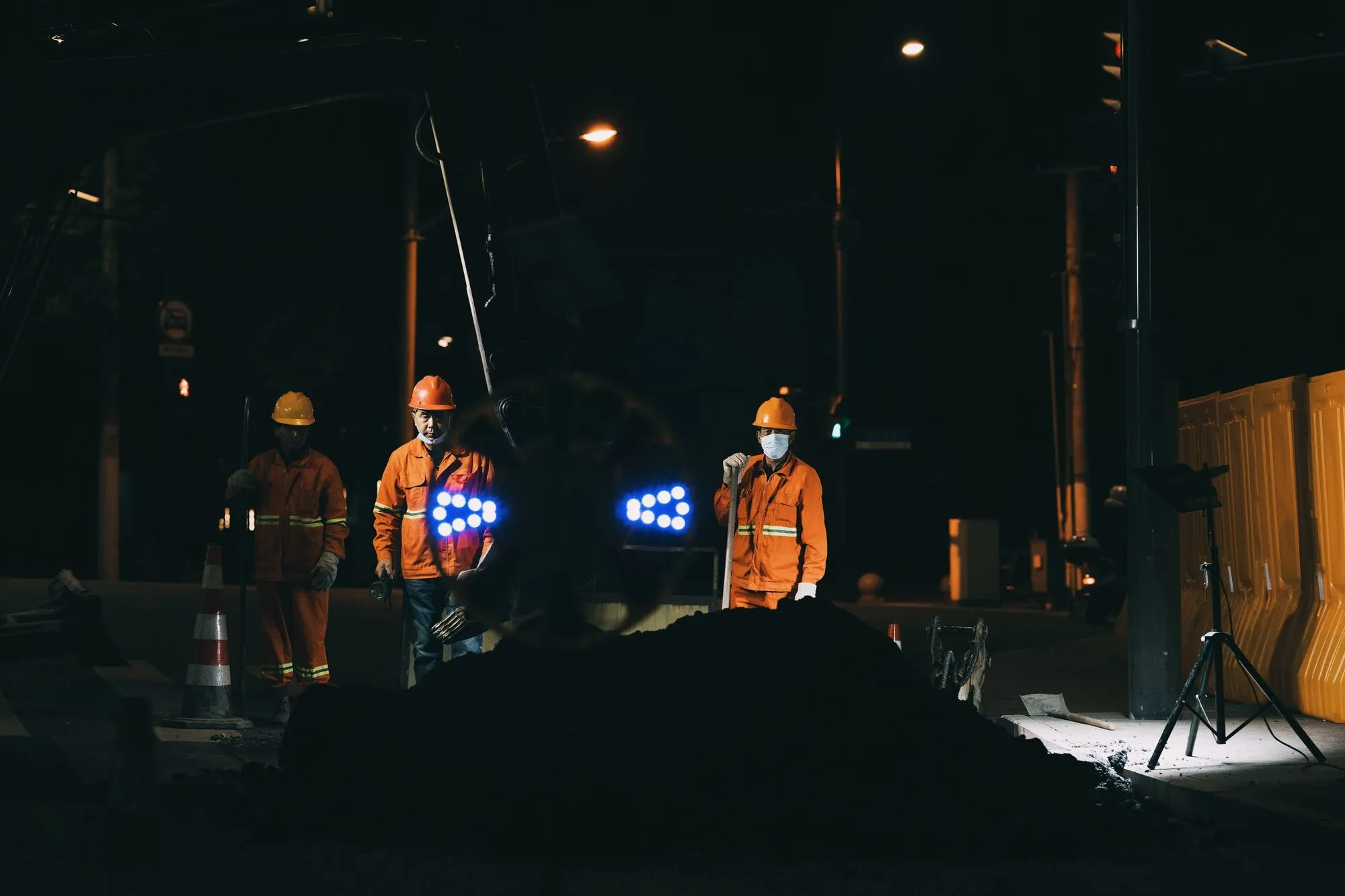 A road crew in hi-vis working a resurfacing job at night under work lights