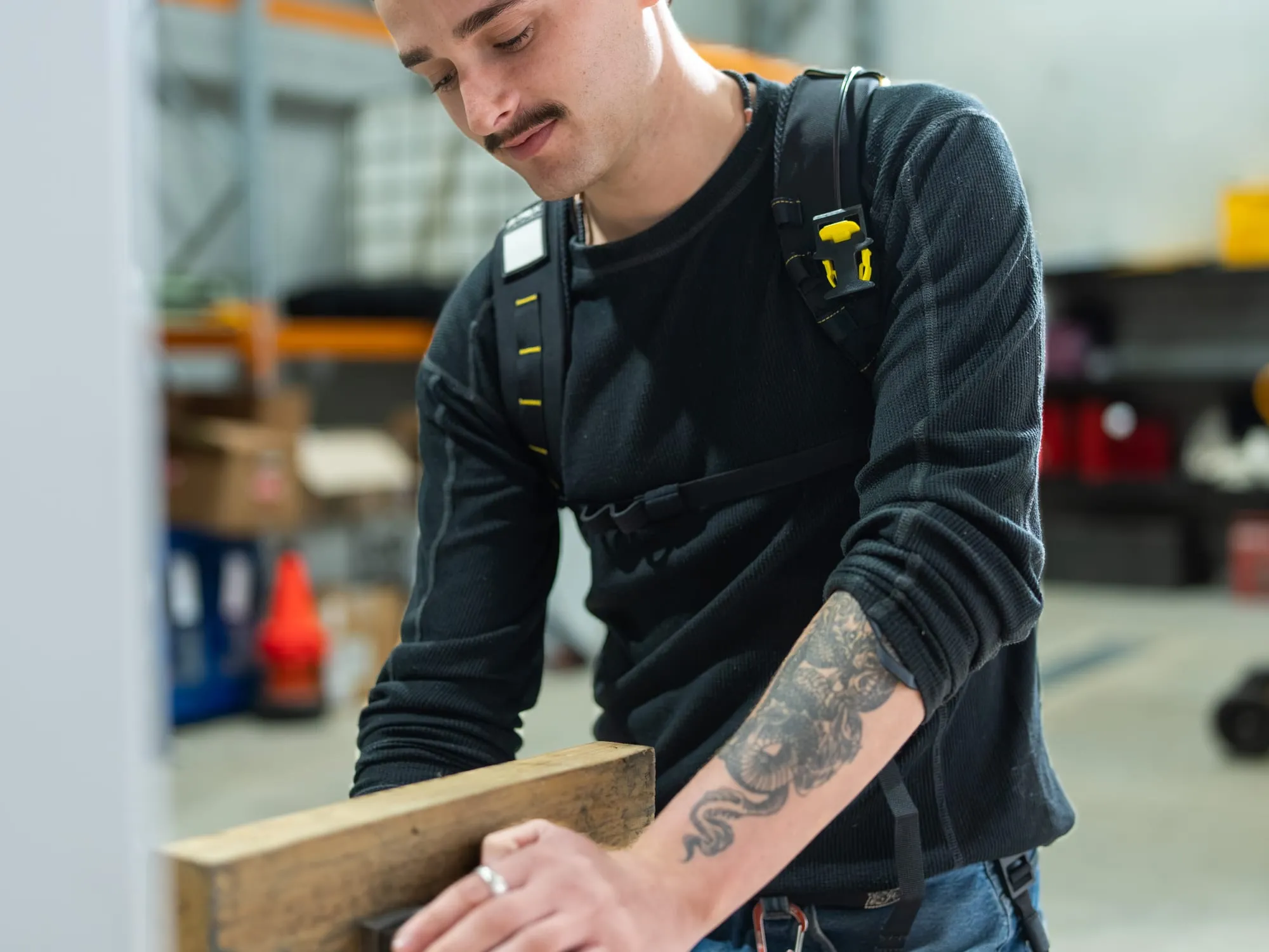 A worker wearing the Apex 2 at a workbench, both hands on a length of timber