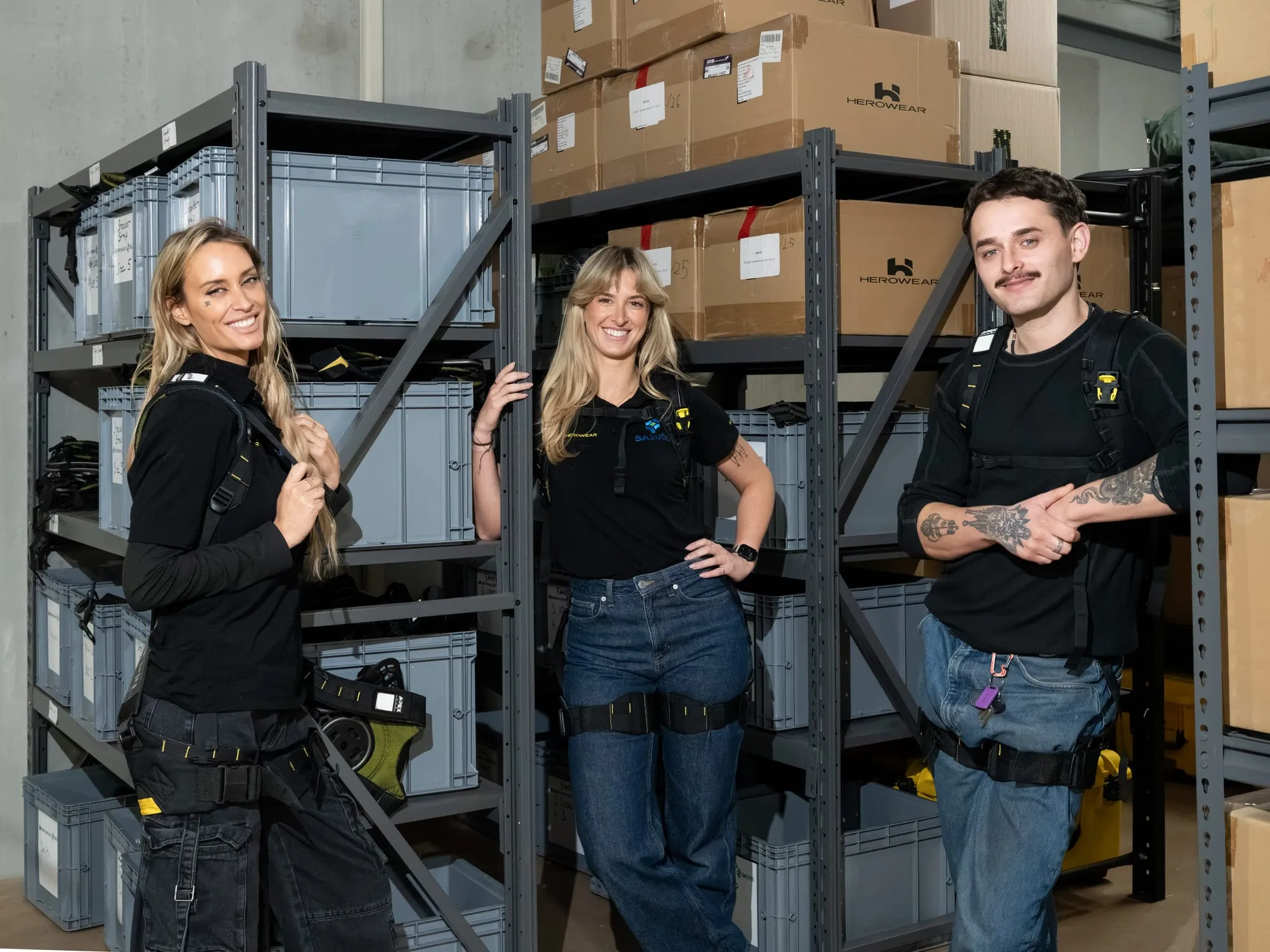 Three SA2050 staff wearing the Apex 2 and standing at storage racking, one of them in a branded polo shirt